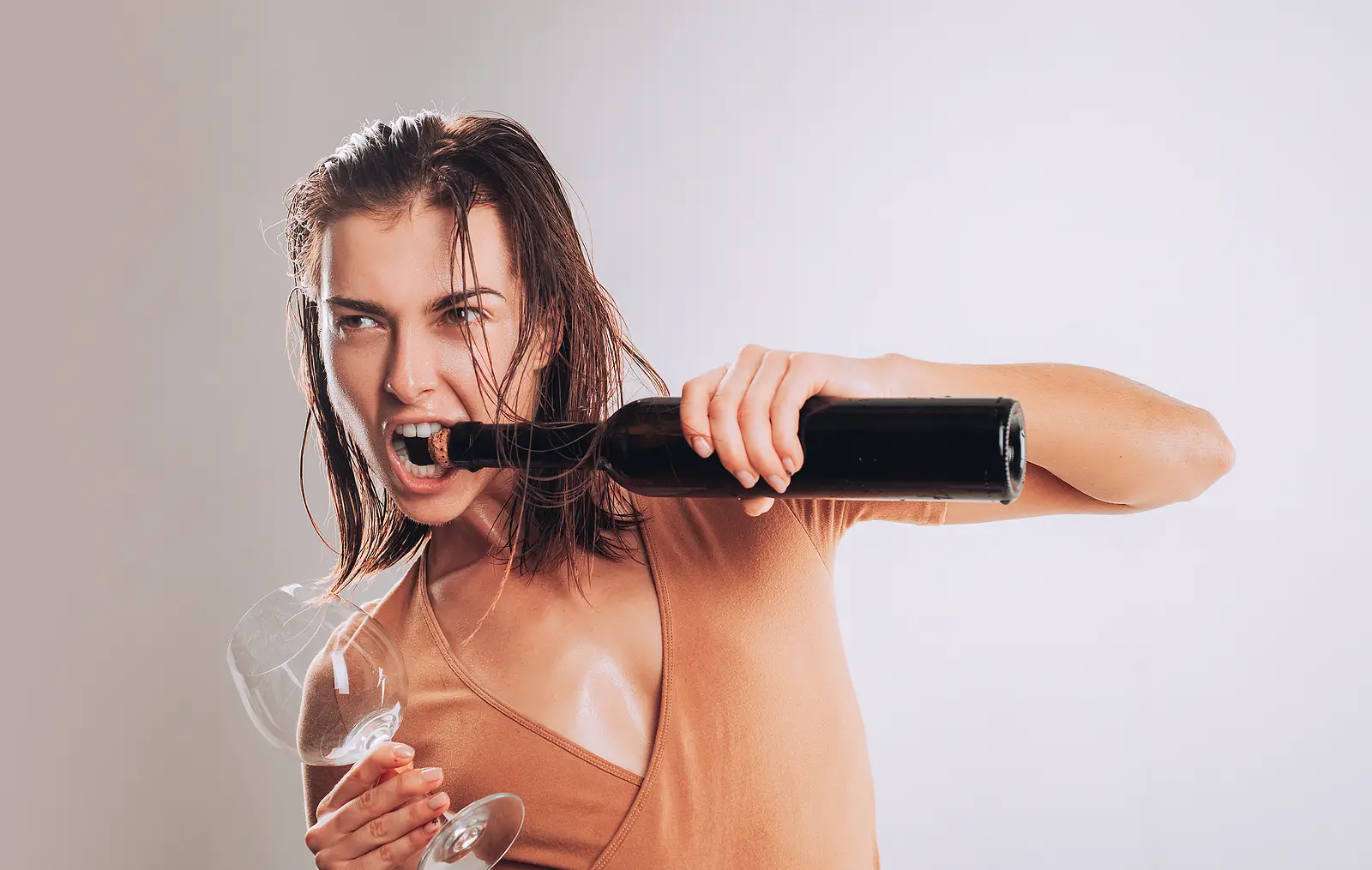 Young women opening bottle with her teeth